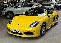 A yellow Porsche 718 Boxster parked outside the workshop