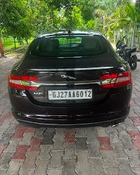 The rear of a black Jaguar XF parked on paving outside
