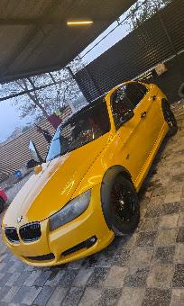 A yellow BMW 3 Series with black alloy wheels parked under the workshop canopy